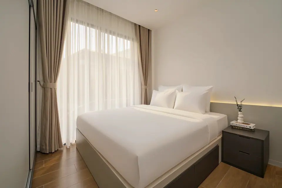 Double bed beside a curtained window