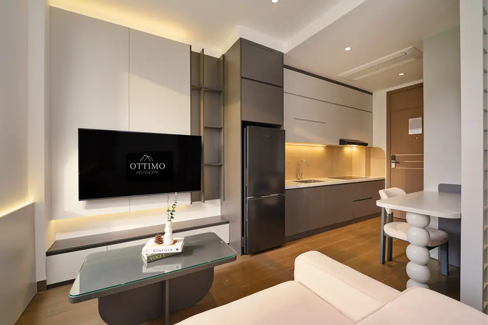 Cream-and-grey studio with a sofa, a TV wall and a kitchen