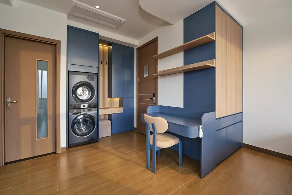 A washer and dryer next to a wardrobe and a work desk