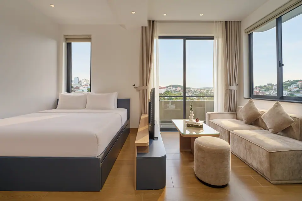 Navy studio with a bed, a sofa and a glass door to the balcony